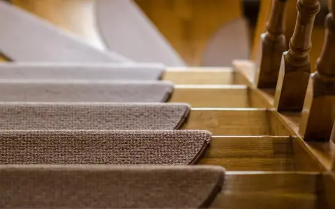 Ciepłe, brązowe schody z wykładziny prowadzą w górę, obok drewnianej balustrady.