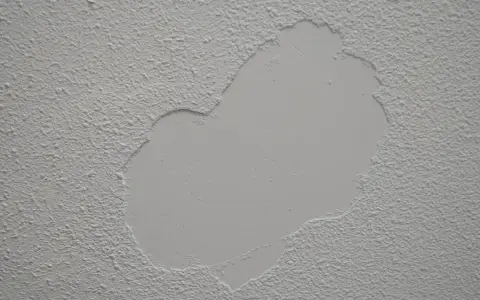 Parche de yeso liso sobre pared con gotelé, listo para lijar y unificar la textura.
