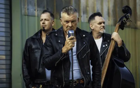 Rock n roll band in Lederjacken. Sänger hält Mikrofon, Bassist spielt Kontrabass, Schlagzeuger hält Sticks.