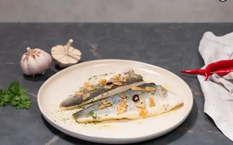 Dos filetes de lubina a la donostiarra, con láminas de ajo dorado, perejil picado y un toque de guindilla.
