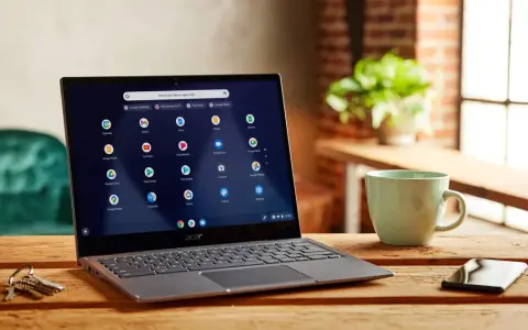 Laptop z systemem Chrome OS Flex na drewnianym stole, obok kubek i klucze.