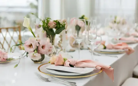 Ett vackert dukat bord med rosa dekorationer, blommor och glas. En elegant dukning för ett speciellt tillfälle.