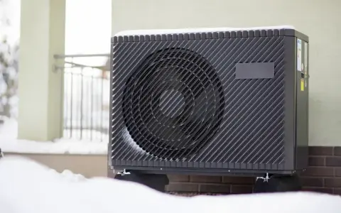 Unité extérieure de climatisation recouverte de neige, signe qu'elle givre.