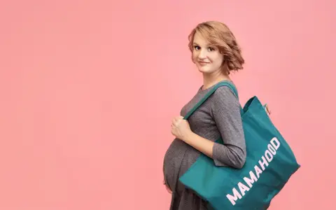 Przyszła mama z torbą "Mamahood" zastanawia się, kiedy spakować torbę do szpitala.