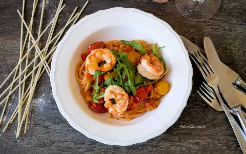Ein köstliches garnelen italienisch rezept: Spaghetti mit Garnelen, Kirschtomaten und Rucola in einer cremigen Sauce.
