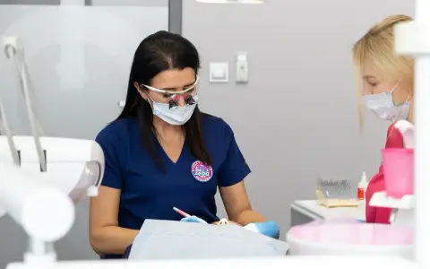 Dentystka w okularach i masce pracuje przy pacjencie. Dyskutują, jak przyspieszyć schodzenie znieczulenia.