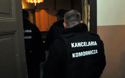 Komornicy w kamizelkach z napisem "KANCELARIA KOMORNICZA" wchodzą do pomieszczenia. Pytanie o alimenty na dziecko ile procent z wynagrodzenia może być związane z ich pracą.