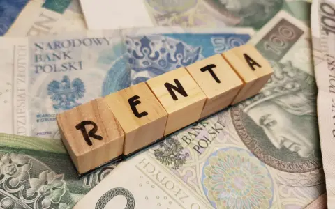 Drewniane klocki z napisem "RENTA" leżą na polskich banknotach.