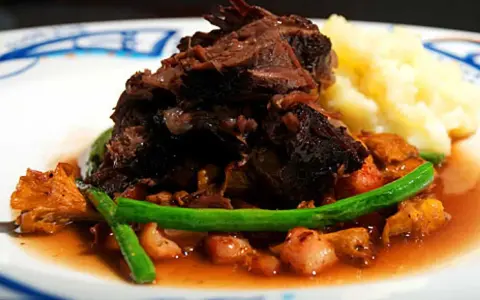 En härlig tallrik med långkokt oxkind, kantareller, gröna bönor och potatismos. Ett perfekt oxkind recept för en festmåltid.