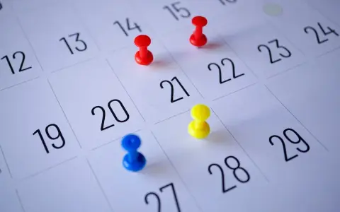 Kolorowe pinezki na kalendarzu pokazują, jak liczyć urlop wypoczynkowy. Planowanie wolnego czasu staje się prostsze.