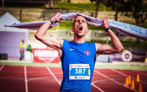 Atleta exhausto, con la boca abierta y una toalla sobre la cabeza, celebra el fin de correr una maratón.