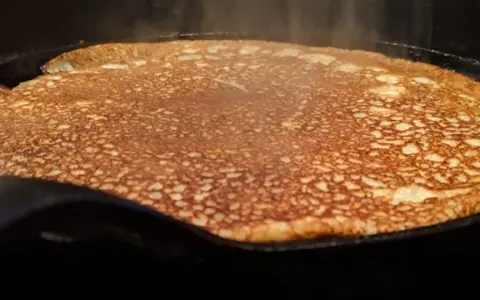 En gyllene, nygräddad pannkaka steker i en gjutjärnspanna. Perfekt för en glutenfri frukost eller fika.
