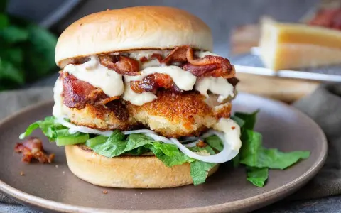 En saftig kycklingburgare med krispigt bacon, sallad, lök och en krämig dressing. Perfekt för ett gott hamburgerdressing recept.
