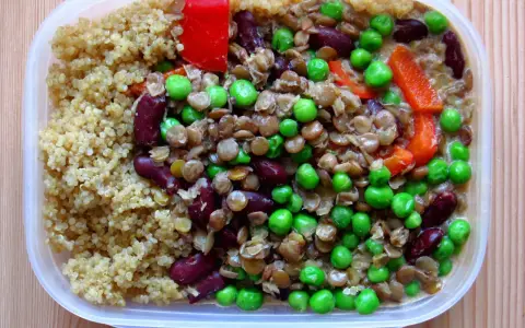 En näringsrik vegetarisk matlåda med quinoa, linser, bönor, ärtor och paprika. Perfekt för en hälsosam lunch.