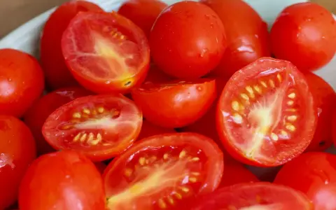 Pomidorki koktajlowe, niektóre przekrojone na pół, na talerzu.