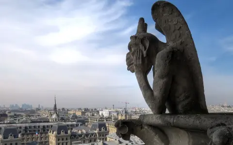 Stryge de Notre Dame, pensif, contemple Paris sous un ciel bleu et nuageux.