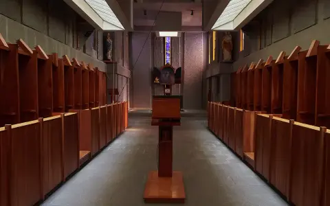 Rows of wooden stalls line the interior of a Carthusian monastery, leading towards an altar.