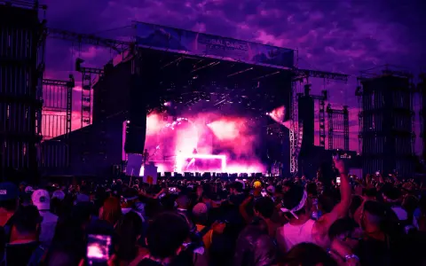Tłum na festiwalu tańca pod fioletowym niebem. Na scenie DJ, dym i światła. To musi być świetny green festival program!