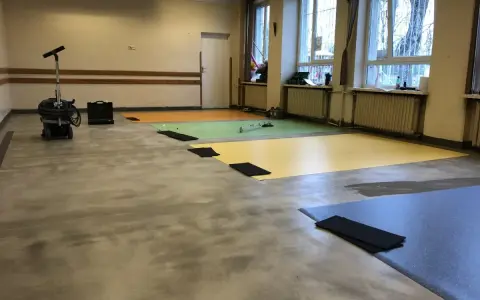 Przygotowanie podłogi pod wykładzinę PCV: odkurzacz przemysłowy i kolorowe maty czekają na ułożenie.