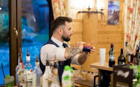 Barman przygotowuje drinki. Czy warto inwestować w barmana i drink bar na weselu? Koszty a efekt - zobacz!