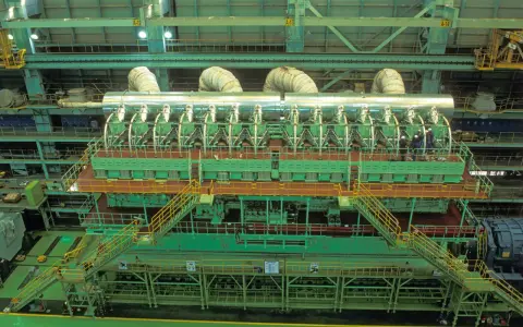 Vue aérienne d'un moteur de bateau massif, le plus gros moteur de bateau jamais construit, avec des ouvriers inspectant son imposante structure verte et argentée.