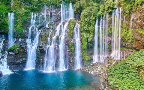 Vackra vattenfall kaskaderar nerför klippor täckta av frodig grönska, ner i en turkos lagun. En idyllisk plats nära Saint-Denis.