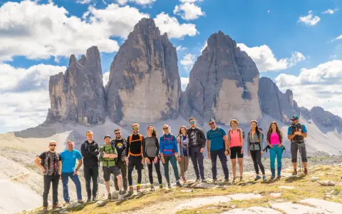 Grupa przyjaciół na tle Tre Cime di Lavaredo podczas niezapomnianego trekkingu w Dolomitach.