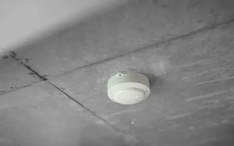En vit brandvarnare monterad i ett betongtak. Denna enhet är avgörande för att veta hur lång tid står en brandcell oftast emot brand.