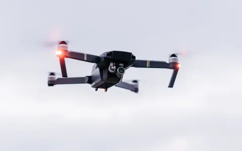 A drone hovers in the sky, its red lights blinking. Planning a trip? Be aware of Bahamas drone laws before you fly.