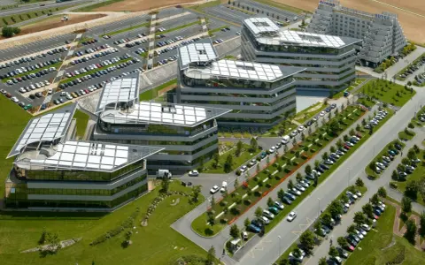 Vue aérienne de bâtiments modernes avec des parkings. On imagine un déjeuner d'affaires au restaurant La Javette.