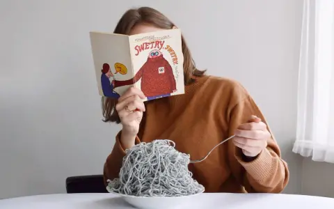 Dziewczyna czyta książkę o swetrach, jedząc spaghetti z włóczki. Jak znaleźć początek włóczki?