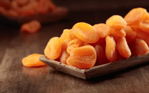 Getrocknete Aprikosen in einer Holzschale, ein gesunder Snack voller Vitamine.