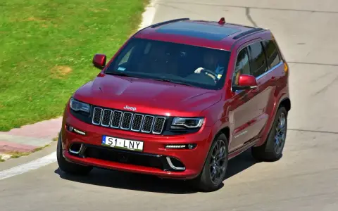Czerwony Jeep Grand Cherokee z indywidualną tablicą rejestracyjną "S1 LNY" na torze wyścigowym.