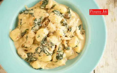 Pyszne gnocchi z kurczakiem i szpinakiem w kremowym sosie, posypane parmezanem. Idealne danie na szybki obiad.