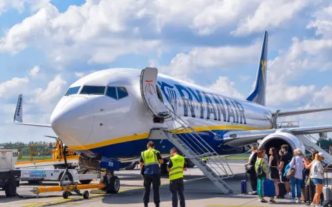 Samolot Ryanair na płycie lotniska z pasażerami i obsługą.