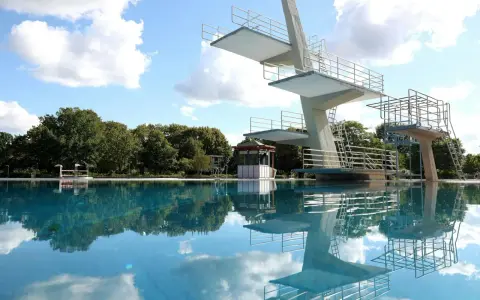 Sprungturm im Schwimmbad Pankow spiegelt sich im klaren Wasser. Ein sonniger Tag lädt zum Sprung ein.