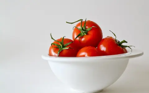 Kilka soczystych pomidorów w białej misce. Zastanawiasz się, ile węglowodanów ma pomidor?