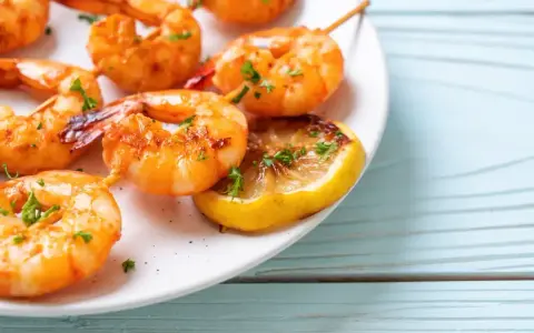 Soczyste krewetki z airfryer, podane z plasterkiem cytryny i posypane natką pietruszki. Idealne na szybką przekąskę.