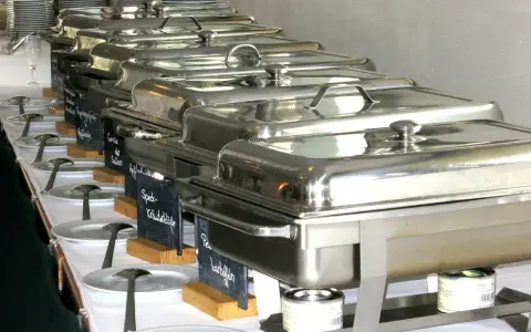 Długi rząd podgrzewaczy z jedzeniem, gotowych do serwowania. To świetny pomysł, jak otworzyć catering i zaimponować gościom.