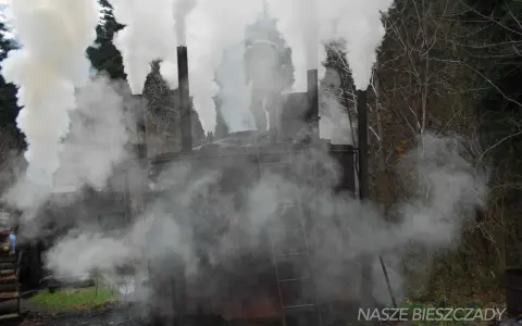 Dymiące retorty w Bieszczadach. Pracownik na szczycie jednej z nich, otoczony gęstą parą.
