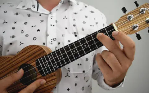 Dłoń dociska struny ukulele, tworząc akord. To jak czytanie tabulatury na gitarze, tylko na mniejszym instrumencie.