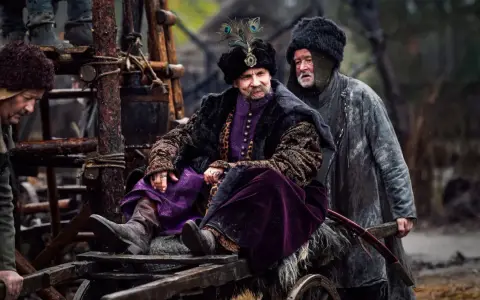 Bogaty pan w purpurowym stroju i futrzanej czapie z pawim piórem, siedzi na wozie. Czy to zapowiedź drugiego sezonu 1670?