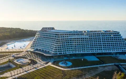 Nowoczesny, falisty pobierowo nowy hotel z basenami i widokiem na morze, otoczony lasem.