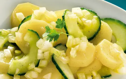 Ein köstlicher Kartoffelsalat mit Gurken, garniert mit Petersilie.