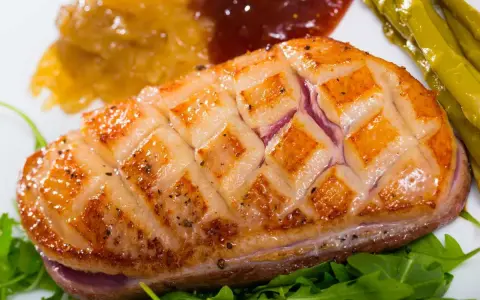Magret de pato perfectamente cocinado, con piel crujiente y jugoso por dentro, acompañado de espárragos y compota.