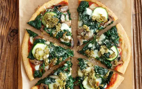 Pyszna pizza ze szpinakiem, cukinią i pieczarkami, polana zielonym pesto. Idealna na lekki obiad.