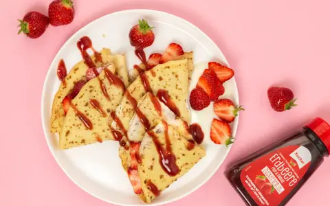 Zarte crepes ohne zucker, garniert mit frischen Erdbeeren und Erdbeer-Topping. Ein Genuss für alle, die es süß, aber zuckerarm mögen.