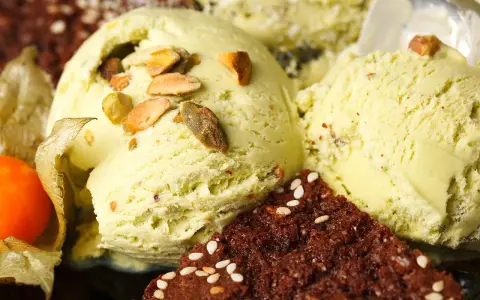 Veganes Eis selber machen: Cremiges Pistazieneis mit Nüssen und Schokostückchen, garniert mit Physalis.