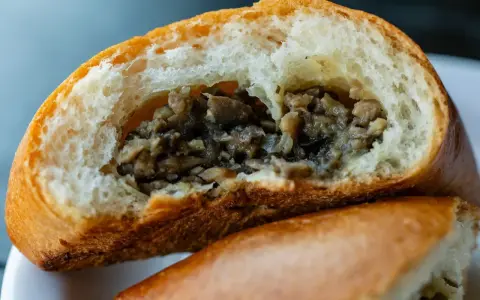 Puszysta bułka z pieczarkami, przekrojona na pół, odsłaniająca aromatyczne, drobno posiekane grzyby.