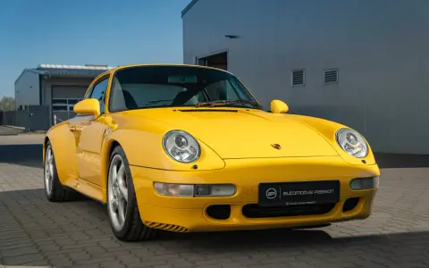 Gelber Porsche 993 vor einem modernen Gebäude. Die Wertentwicklung dieses Klassikers ist bemerkenswert.